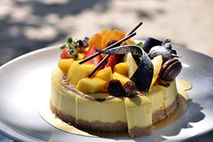 A cheesecake with fruit and fancy chocolate decorations on top